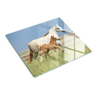 Tabla para cortar Un caballo con un potro en un prado.