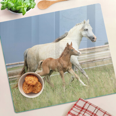 Tabla para cortar Un caballo con un potro en un prado.