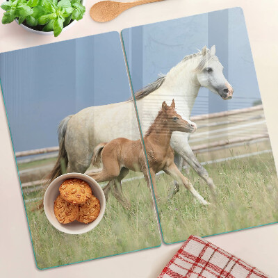 Tabla para cortar Un caballo con un potro en un prado.