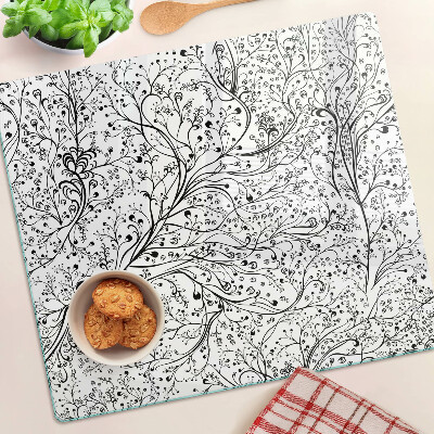 Tabla de cortar de cristal Un patrón de planta con ramas delicadas.