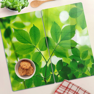 Tabla de cortar de cristal Hojas sobre un fondo verde