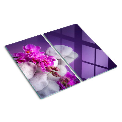 Tabla de cortar de cristal Flores de orquídea sobre un fondo de piedras.
