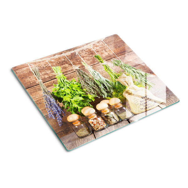 Tabla de cortar de cristal Hierbas y especias sobre un fondo de madera.