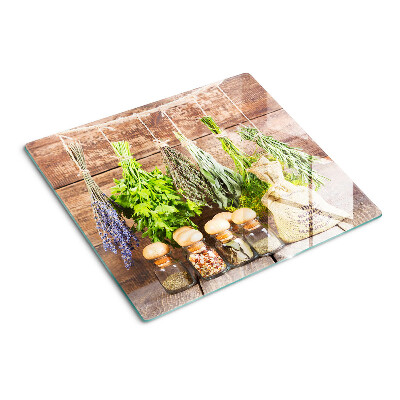Tabla de cortar de cristal Hierbas y especias sobre un fondo de madera.
