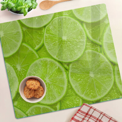 Tabla de cortar de cristal Rodajas de lima sobre un fondo verde