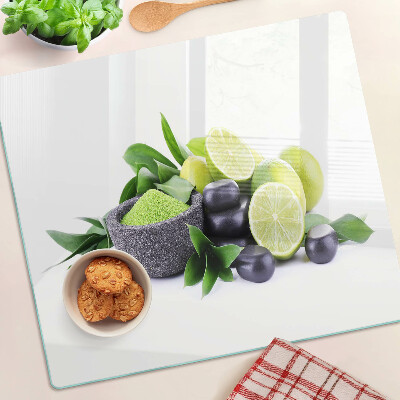 Tabla de cortar de cristal Limones y uvas sobre un fondo verde.