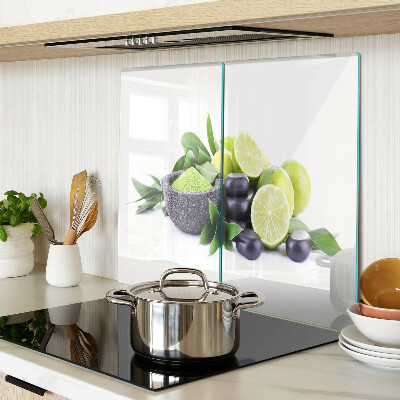Tabla de cortar de cristal Limones y uvas sobre un fondo verde.