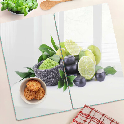 Tabla de cortar de cristal Limones y uvas sobre un fondo verde.