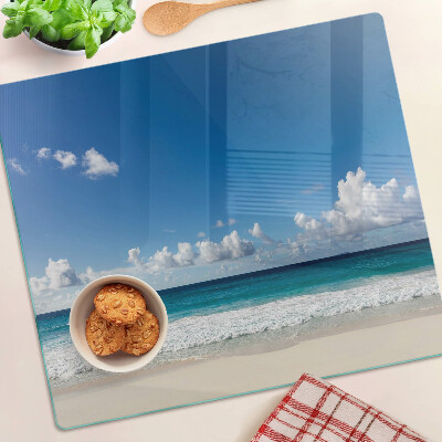 Tabla para cortar Playa con agua turquesa y nubes.