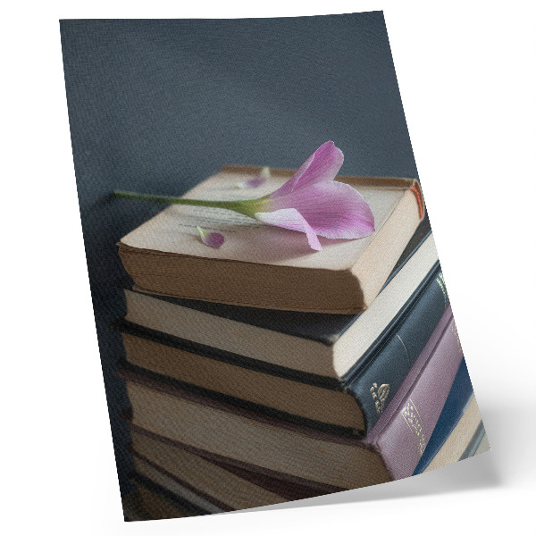 Póster con colores saturados Una pila de libros con una delicada flor encima.