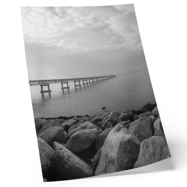 Póster con colores saturados Paisaje tranquilo, puente, playa rocosa, cielo gris