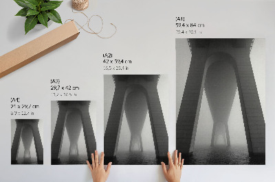 Póster Construcción de un puente en medio de una densa niebla cerca del agua.