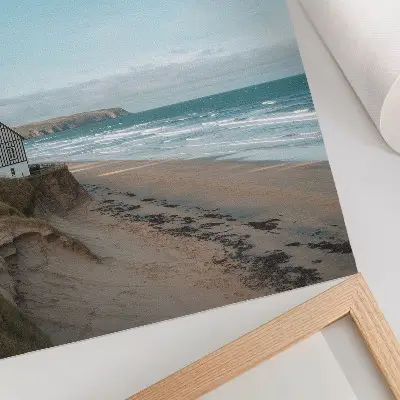 Póster playa con olas y casa en un acantilado en colores pastel
