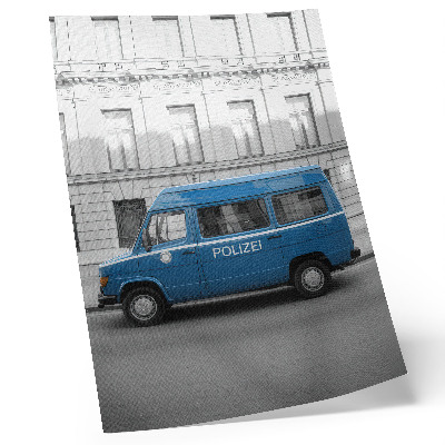 Póster Un coche de policía azul con un edificio al fondo.