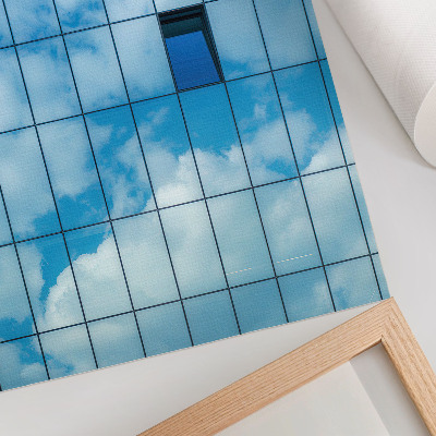 Póster Una fachada de cristal que refleja el cielo y las nubes.