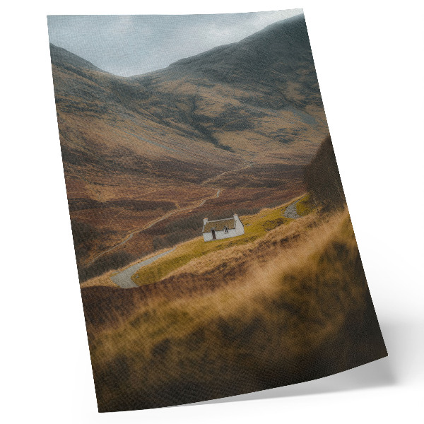 Póster Un paisaje montañoso con una cabaña solitaria en medio de la naturaleza.