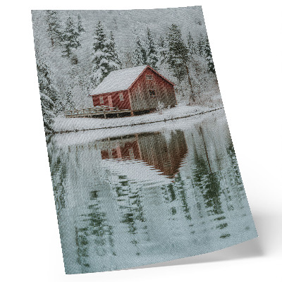 Lámina artística de alta calidad Una casita roja entre árboles nevados junto al agua.