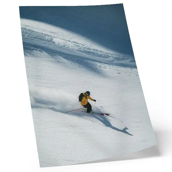 Póster esquiador con chaqueta amarilla en una ladera nevada con sombra