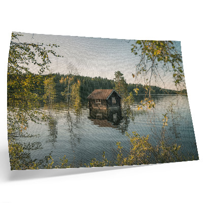 Póster Cabaña junto al lago con el reflejo del agua del bosque como telón de fondo, en un ambiente de paz.