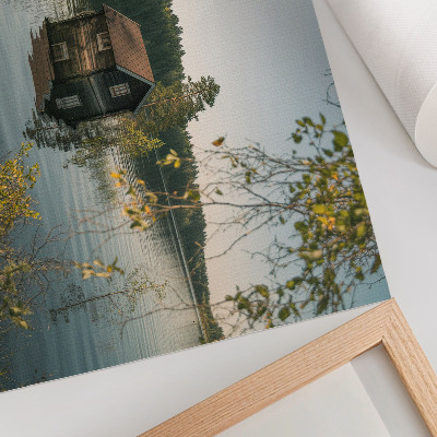 Póster Cabaña junto al lago con el reflejo del agua del bosque como telón de fondo, en un ambiente de paz.