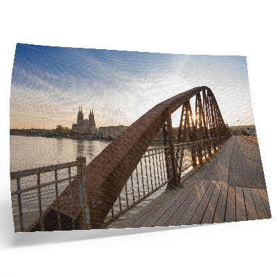 Póster puente metálico sobre el río frente a la catedral al atardecer