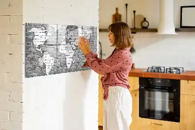 Pizarra magnética de pared con diseño de mapa del mundo sobre ladrillos y rotulador